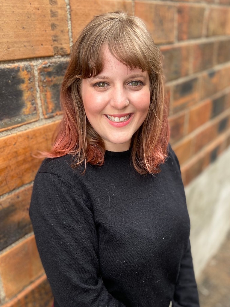Holly Hartman head shot with brick wall behind